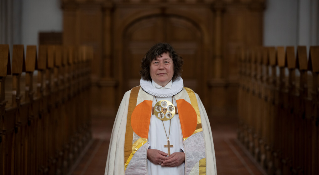 Biskop over Haderslev Stift Marianne Christiansen står midt i kirken og smiler mildt til kameraet