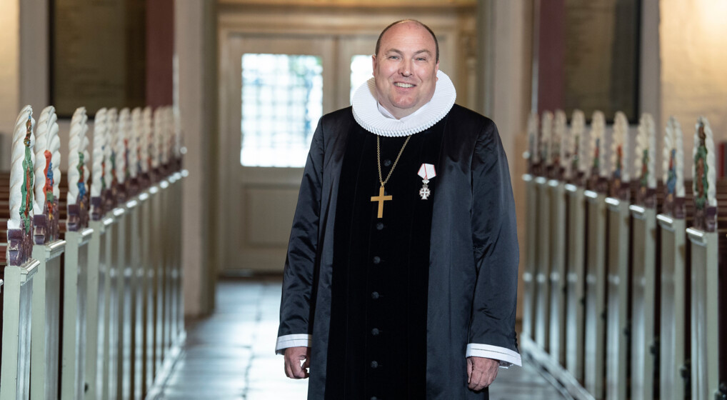 Biskop i Aalborg Stift Thomas Reinholdt Rasmussen står midt i kirken og smiler til kameraet